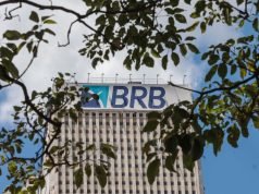 Topo de prédio do BRB (Banco de Brasília) em meio a folhas de árvores