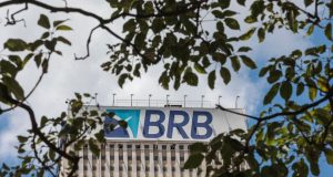 Topo de prédio do BRB (Banco de Brasília) em meio a folhas de árvores