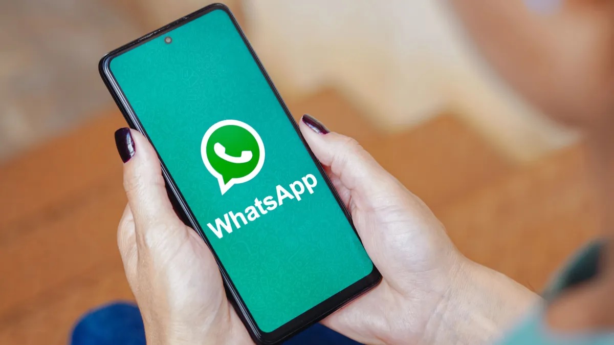 Mãos mexendo em celular com logo do whatsapp