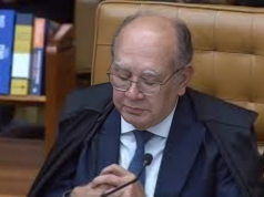 ministro Gilmar Mendes de cabeça baixa, de óculos de grau