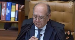ministro Gilmar Mendes de cabeça baixa, de óculos de grau