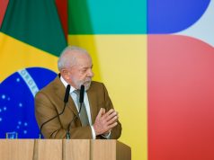 O presidente Luiz Inácio Lula da Silva (PT) de roupa social marrom, falando e gesticulando, olhando para o lado