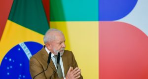 O presidente Luiz Inácio Lula da Silva (PT) de roupa social marrom, falando e gesticulando, olhando para o lado