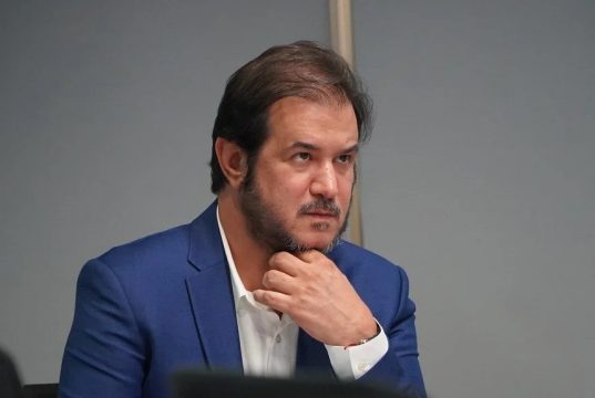 O presidente do União Brasil, Antonio Rueda, sério, com uma das mãos no queixo