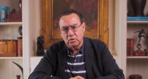 O escritor e psiquiatra Augusto Cury falando para a câmera, de óculos de grau, sentado