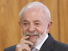 O presidente Luiz Inácio Lula da Silva (PT) com um dedo na boca, sorrindo, em close, sem olhar para a câmera