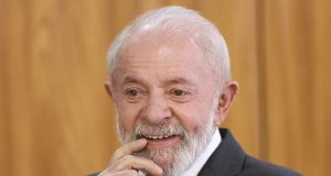 O presidente Luiz Inácio Lula da Silva (PT) com um dedo na boca, sorrindo, em close, sem olhar para a câmera