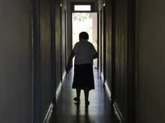 Idosa andando em corredor, de costas