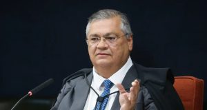 O ministro Flávio Dino, do Supremo Tribunal Federal (STF), sentado, falando e gesticulando, de óculos de grau