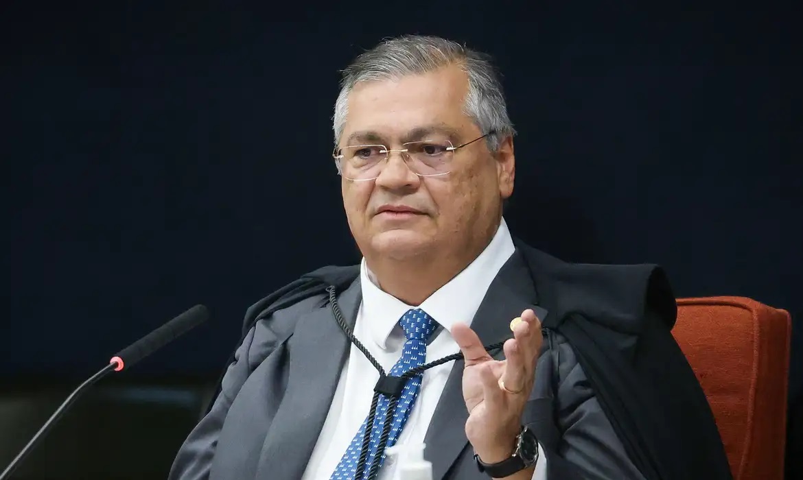 O ministro Flávio Dino, do Supremo Tribunal Federal (STF), sentado, falando e gesticulando, de óculos de grau