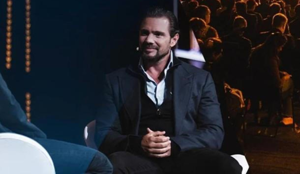 empresário Daniel Vorcaro, dono do Banco Master, sentado, sorrindo, sem olhar para a câmera