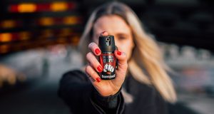 Mulher apontando spray de pimenta para a câmera