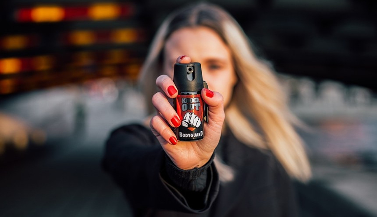 Mulher apontando spray de pimenta para a câmera