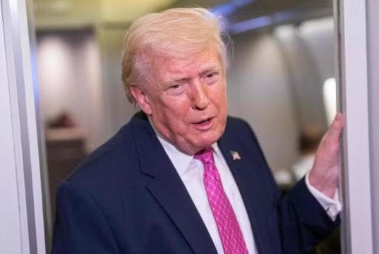 O presidente Donald Trump em pé, falando, de roupa social