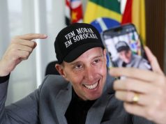 Rodrigo Manga (Republicanos) de boné, sorrindo e olhando para celular