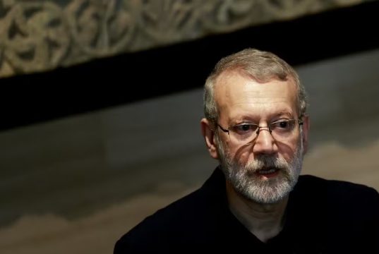 Ali Larijani, chefe do Conselho Supremo de Segurança do Irã, sério, em canto direito de foto, de óculos