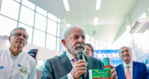O presidente Luiz Inácio Lula da Silva (PT) segurando caixas de remédio e falando em microfone