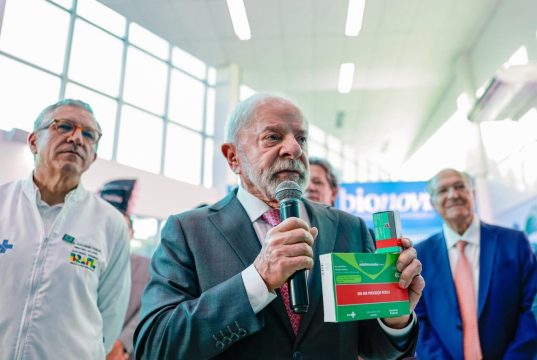 O presidente Luiz Inácio Lula da Silva (PT) segurando caixas de remédio e falando em microfone