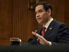 O secretário de Estado dos EUA, Marco Rubio, em pé, falando e gesticulando, sério, sem olhar para a câmera