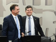 Os senadores Flavio Bolsonaro (PL) e Sergio Moro (União) em pé, lado a lado, sorrindo