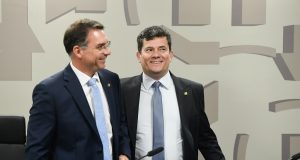 Os senadores Flavio Bolsonaro (PL) e Sergio Moro (União) em pé, lado a lado, sorrindo