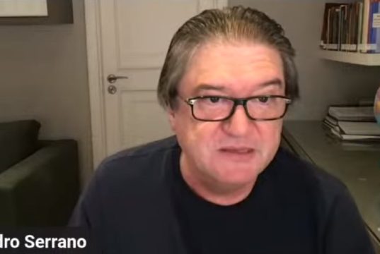 O jurista Pedro Serrano de óculos de grau e camiseta preta, falando para a câmera