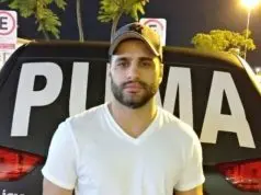 Luiz Phillipi Mourão, conhecido como “Sicário”, posando para foto de camiseta branca e boné, sério, olhando para a câmera