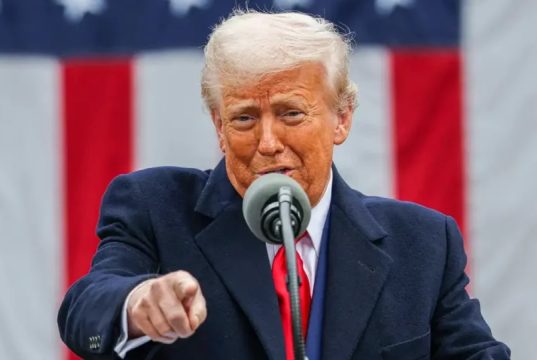 O presidente americano Donald Trump falando em microfone e apontando pra frente