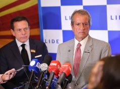 Valdemar Costa Neto sério, perto de microfones, em pé