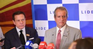 Valdemar Costa Neto sério, perto de microfones, em pé