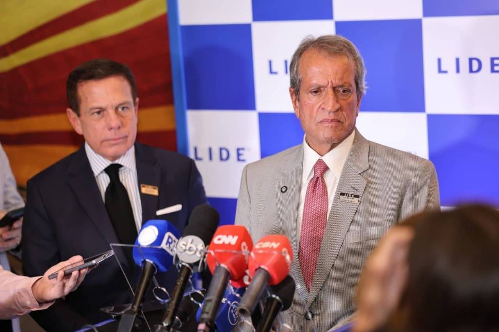 Valdemar Costa Neto sério, perto de microfones, em pé