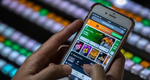 Mãos mexendo em celular aberto em site de apostas