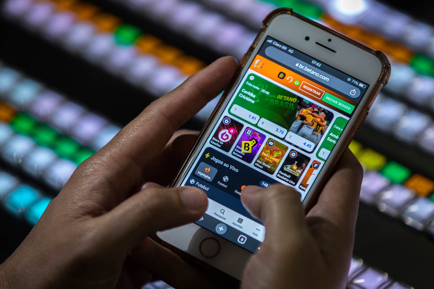 Mãos mexendo em celular aberto em site de apostas