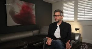 Wagner Moura sentado, falando e gesticulando