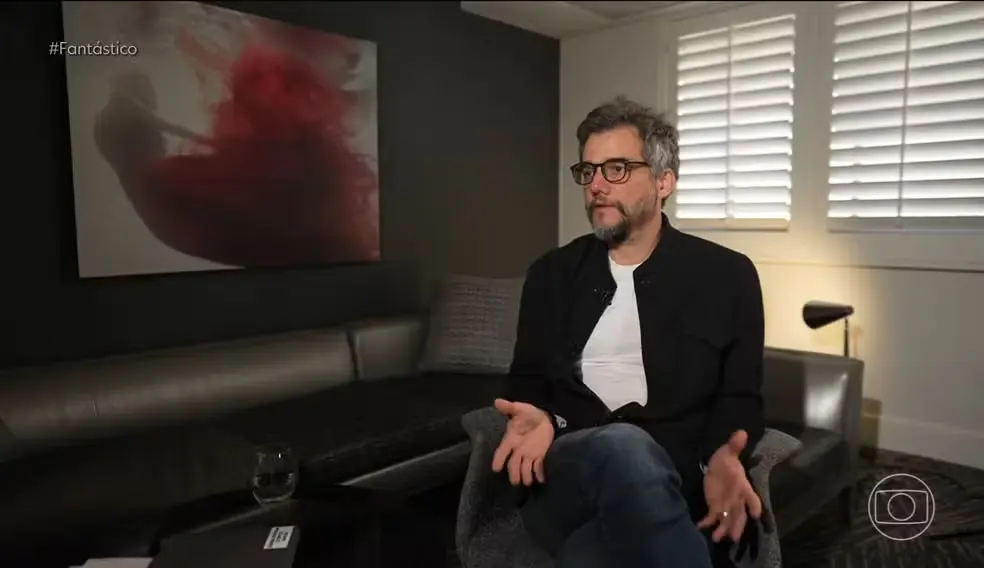 Wagner Moura sentado, falando e gesticulando