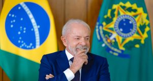 Lula sorrindo, com os braços cruzados, olhando para o lado