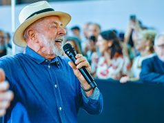 presidente Lula de camisa jeans e chapéu, falando em microfone