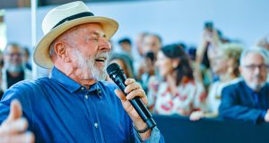 presidente Lula de camisa jeans e chapéu, falando em microfone