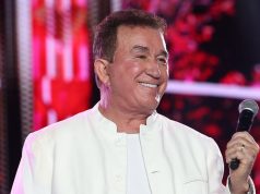 O cantor Amado Batista sorrindo, de roupa branca, olhando para o lado