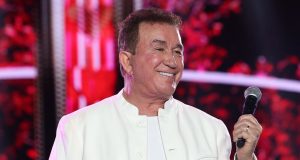 O cantor Amado Batista sorrindo, de roupa branca, olhando para o lado