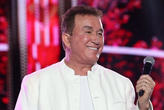 O cantor Amado Batista sorrindo, de roupa branca, olhando para o lado