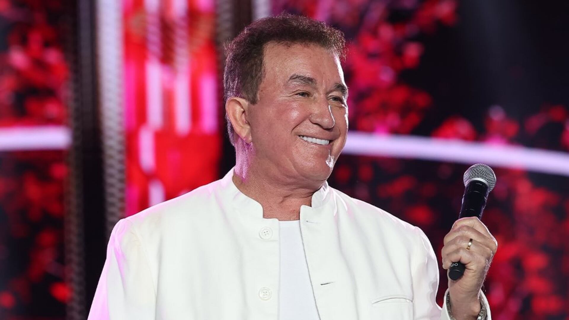 O cantor Amado Batista sorrindo, de roupa branca, olhando para o lado