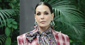 Carolina Ferraz de cabelo preso e roupa estampada, séria, olhando para a câmera