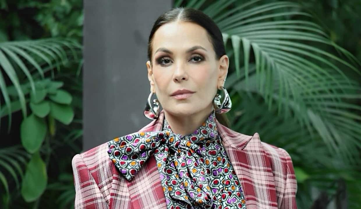 Carolina Ferraz de cabelo preso e roupa estampada, séria, olhando para a câmera