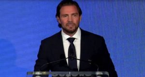 O empresário Daniel Vorcaro em pé, falando, sério