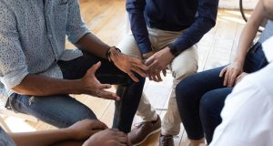 Pessoas sentadas em círculo sem mostrar o rosto