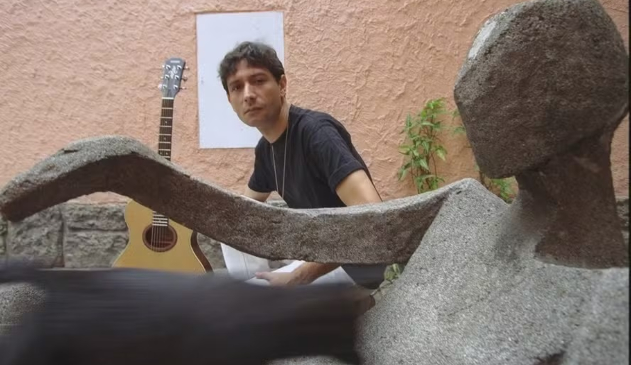 O compositor brasileiro Alvin L sério, olhando para a câmera, de camiseta preta