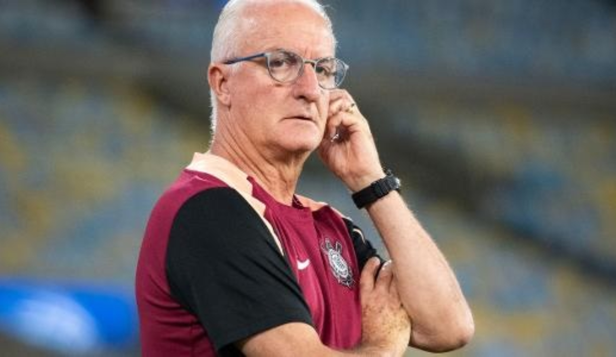 técnico Dorival Júnior sério, de óculos de grau, com uma mão em uma orelha