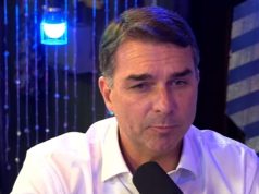 O pré-candidato à Presidência da República Flávio Bolsonaro (PL) falando em microfone, sério, de roupa clara