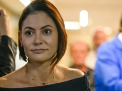 A ex-primeira-dama Michelle Bolsonaro no canto esquerdo da foto, com expressão de espanto